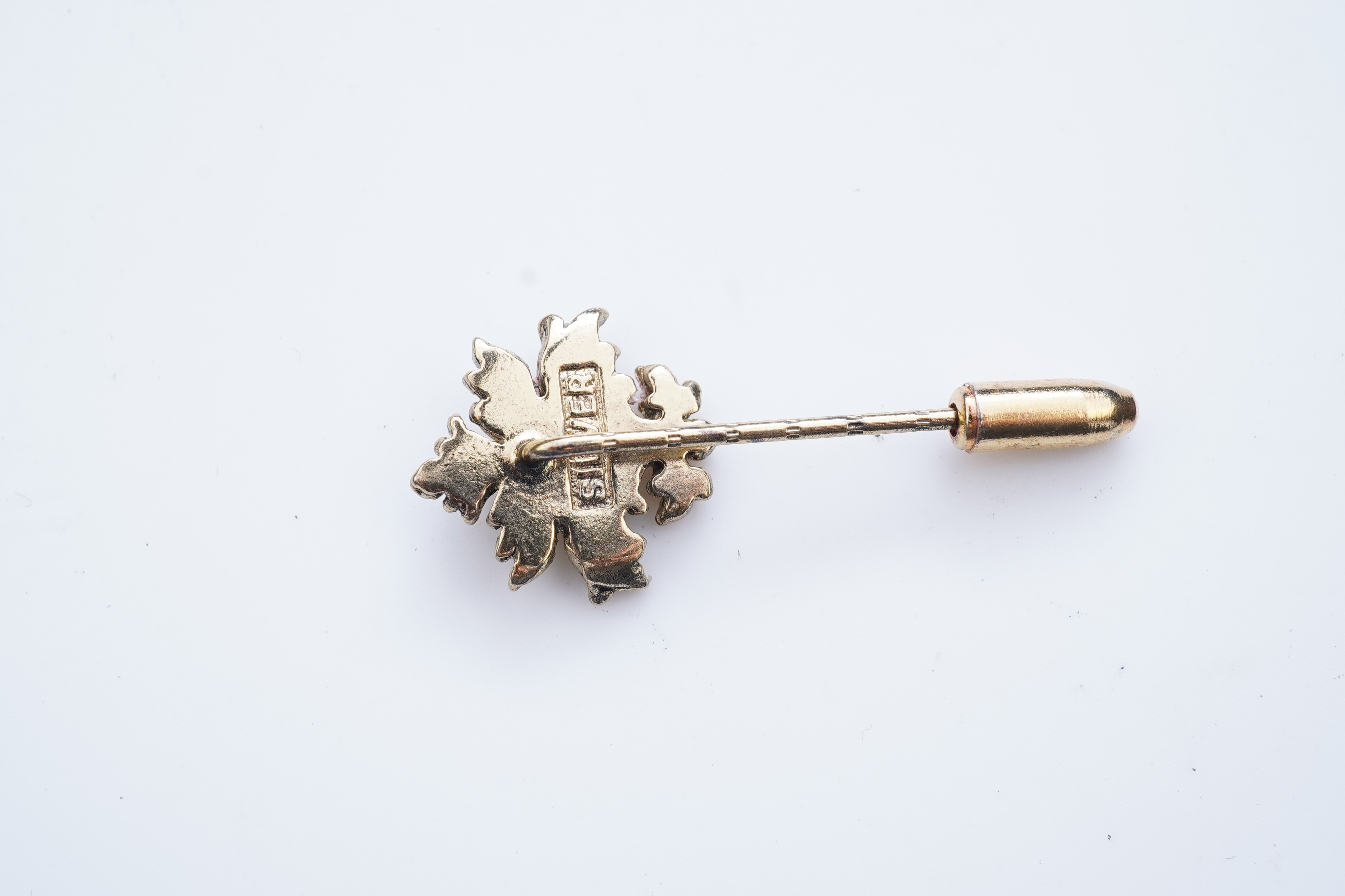 A collection of six stick pins, comprising: three gold stick pins, one set with a hardstone cameo, Austrian assay marks; a gold stick pin with a faceted edge; and a gold stick pin of Masonic design, stamped 9CT, combined